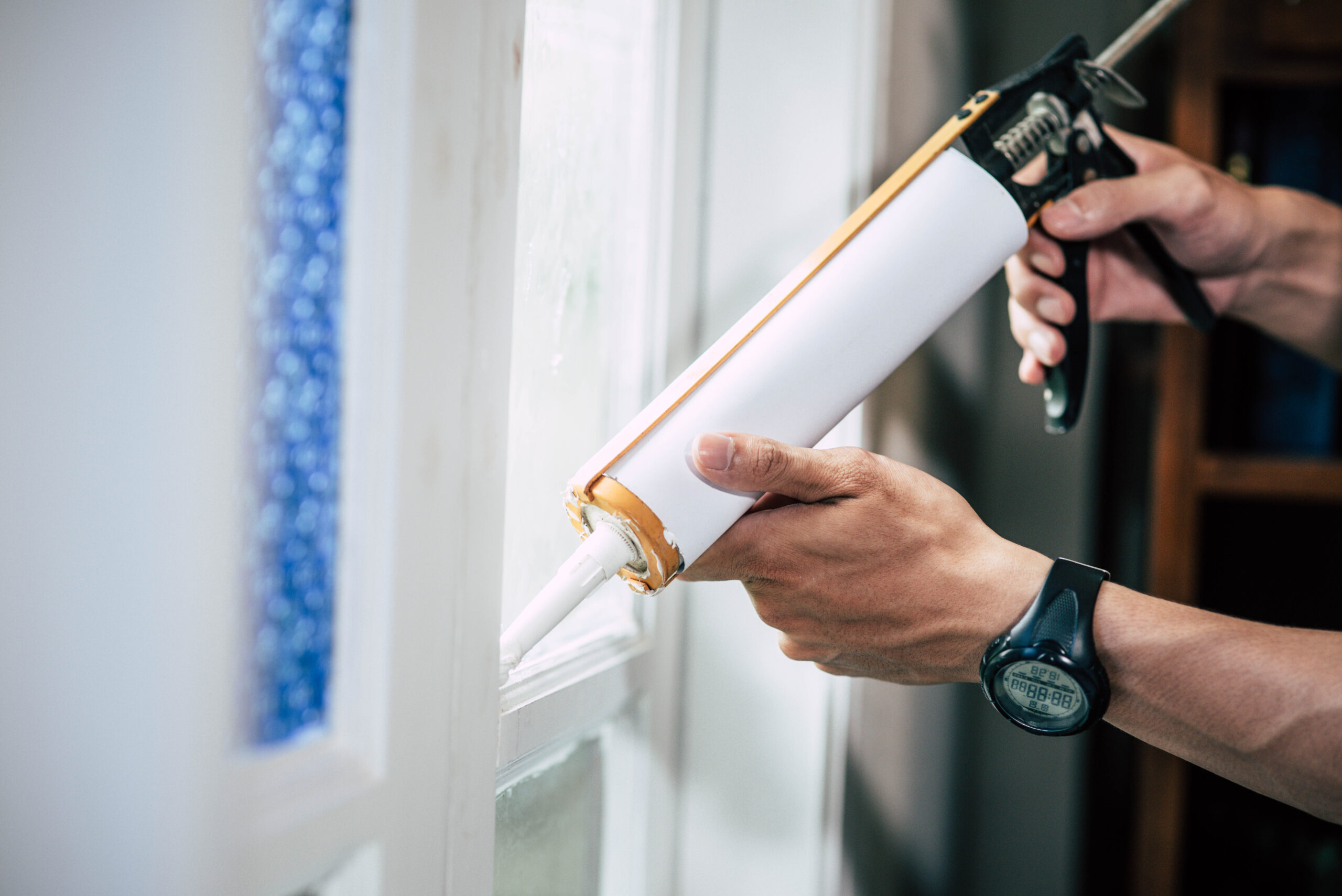 The carpenter holds the glue and attaches to the window. Selective focus.